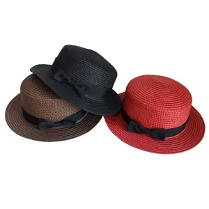 Detail view of woven straw flat top hat with black ribbon bow, breathable summer beach sun hat