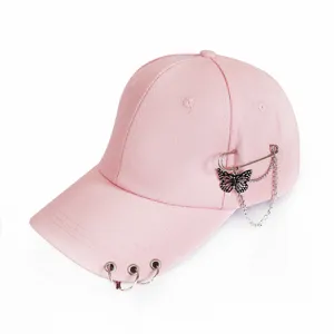 Pink baseball cap detail view, featuring metal rings on brim and butterfly chain side decor.