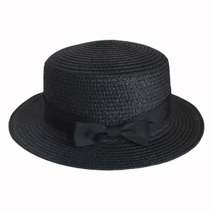 Close-up details of the black straw boater hat with elegant bow ribbon. Perfect sun protection.