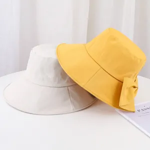 Détail de chapeaux bob d'été avec nœud en jaune et beige pour la protection solaire