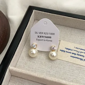 Nahaufnahme von Perlenohrringen mit Zirkonia auf einer S925-Silber-Exportkarte