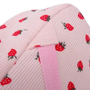 Macro detail of pink corduroy fabric with cute red strawberry print on a school backpack