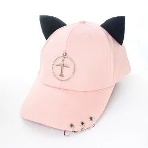 Détail d'une casquette rose avec des oreilles de chat noires et des anneaux en métal