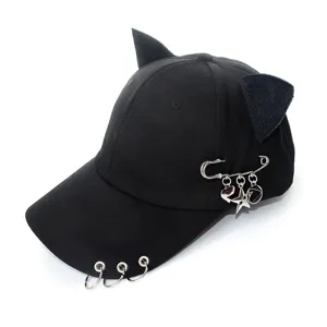 Close-up of black cat ear baseball cap featuring metal rings on brim and safety pin charms.