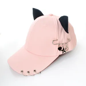 Pink baseball cap with black cat ears, metal rings, and pin charms for street style.