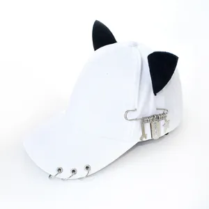 Detail view of white streetwear baseball cap with black cat ears and metal pin charms.