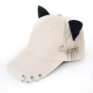 Cat ear baseball cap detail showing metal rings brim and punk safety pin charm design.