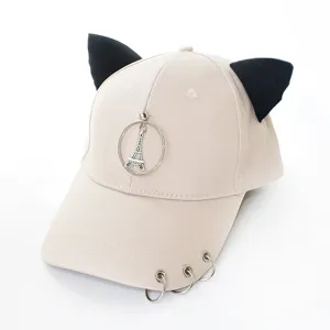 Détail d'une casquette beige avec oreilles d'animaux noires et breloque tour Eiffel