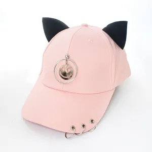 Vue détaillée d'une casquette rose avec des oreilles de chat et des anneaux argentés.