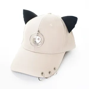 Vue détaillée de la casquette beige avec oreilles de chat, anneaux métalliques et pendentif smiley