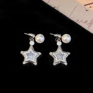 Close-up detail of micro-paved zircon star earrings with elegant pearls.