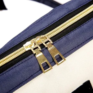Detailopname van gouden dubbele ritsen op een duurzame tas van donkerblauwe nylon stof