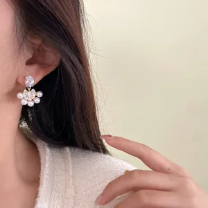 Elegantes pendientes en forma de abanico con perlas y circonitas en la oreja del modelo