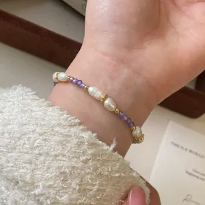 Primer plano de una pulsera artesanal con perlas de agua dulce y piedras naturales violetas.