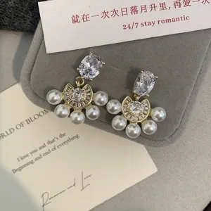 Vista detallada de pendientes en forma de abanico con perlas blancas y circonitas