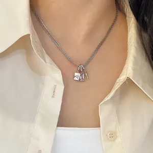 Detailansicht einer dreilagigen Silberkette mit rosa Zirkonia- und Briefumschlag-Anhängern