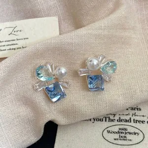 Primo piano di orecchini eleganti con zircone blu quadrato e perle bianche
