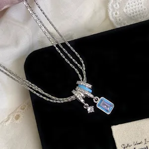 Makroansicht einer dreilagigen Halskette mit blauem Emaille und Zirkonia-Anhänger.