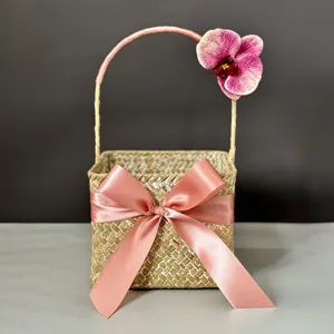 Close-up detail of handcrafted seagrass woven gift basket with elegant pink ribbon bow.