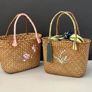 Sac à main tissé en jonc de mer avec motif floral brodé et poignées ruban pour cadeaux.