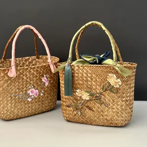 Panier tissé en jonc de mer fait main avec broderie florale délicate et poignées élégantes.