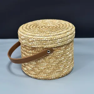 Vista detallada de una cesta de regalo redonda de paja tejida a mano con asa de cuero marrón