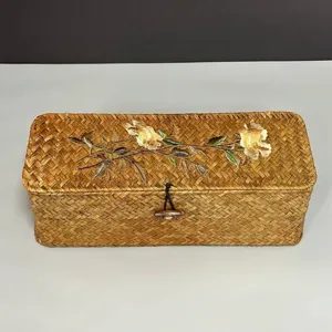 Detail view of hand-woven seagrass storage box with elegant floral embroidery decoration