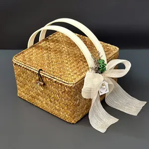 Gros plan de la boîte cadeau en paille tissée avec poignées blanches et joli nœud.
