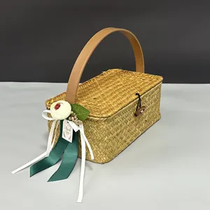 Handmade rattan gift basket with lid, leather handle, and floral decoration for wedding storage.
