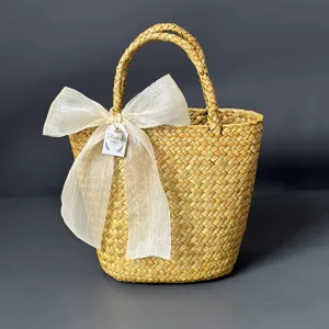 Handmade straw woven gift basket with elegant white bow ribbon, perfect for pastoral decor.