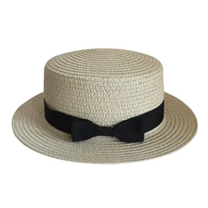 Detailed view of summer flat top straw hat with black ribbon bow for outdoor sun protection.