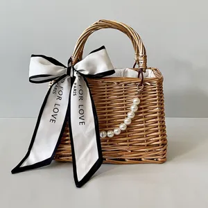 Detail of handmade wicker basket bag with large satin bow and pearl chain decoration.