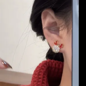 Primo piano di un orecchino a bottone scintillante a forma di renna di Natale su modella.