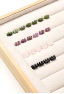 Detail showing rows of cylindrical stone beads in various colors on a velvet jewelry tray.