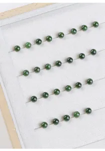 Macroweergave van ronde jaspis-jade kralen in spinaziegroen op wit sieradendisplay