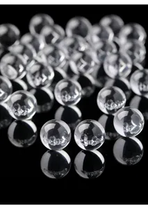 Primer plano de cuentas de cristal blanco natural transparente sobre fondo negro reflectante