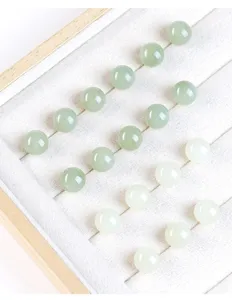 Macro detail of natural Hetian jade round beads arranged in a white velvet jewelry tray