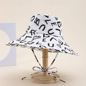 Close-up of wide-brim bucket hat with artistic brush-stroke letter print and chin drawstring.
