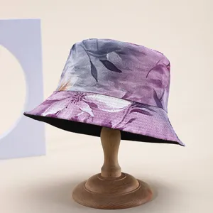 Detailed view of a reversible bucket hat with elegant purple floral print on a wooden stand.