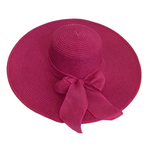 Detailed view of a fuchsia rose red wide brim straw sun hat with a large decorative bow