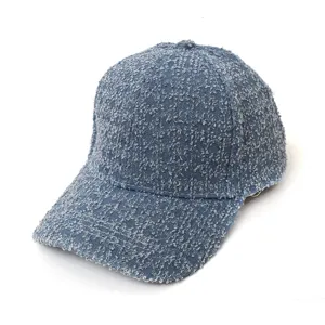 Close-up detail of textured blue fabric baseball cap, showing curved brim and stitching.