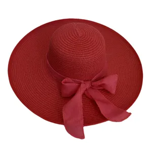 Close-up of a red woven straw sun hat with a wide brim and decorative bow