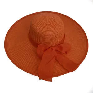 Close-up view of a vibrant orange wide-brim straw hat with an elegant ribbon bow detail.