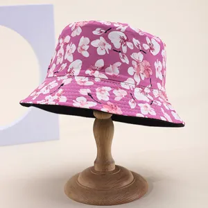 Detailed view of a pink bucket hat with white cherry blossom floral print on a stand