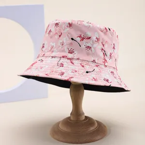 Detailed view of a reversible floral bucket hat with cherry blossom print on a wooden stand