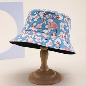 Detailed studio shot of a reversible blue sun hat with pink cherry blossom floral print