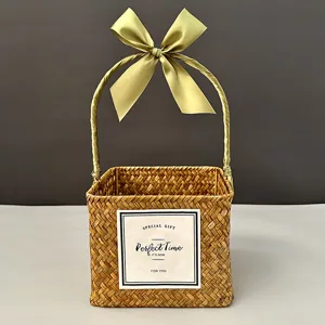 Macro detail of a handmade square woven straw gift basket with a green silk ribbon bow
