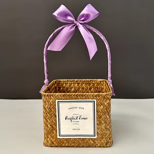 Hand-woven square straw gift basket featuring a purple ribbon handle and decorative label