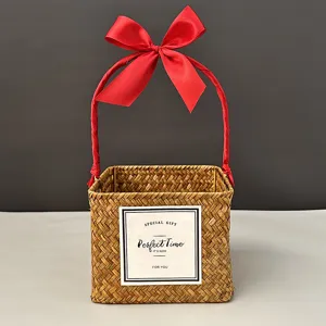 Macro view of woven square gift basket featuring a festive red ribbon handle