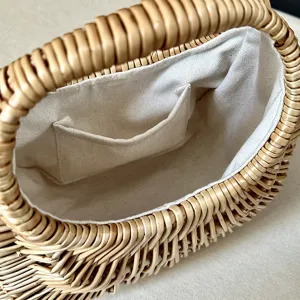 Detailed view of the woven rattan handbag interior, featuring a neat fabric lining and small pocket.